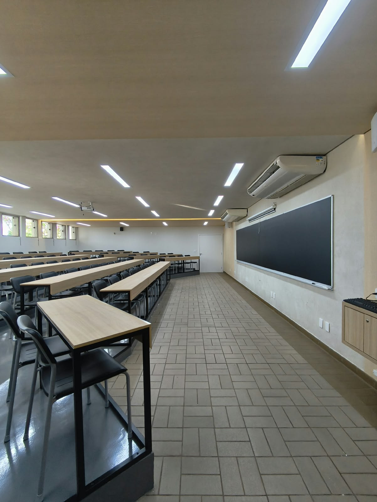 Sala do cursinho do Colégio Anglo com bancadas em diferentes níveis e iluminação direcionada.